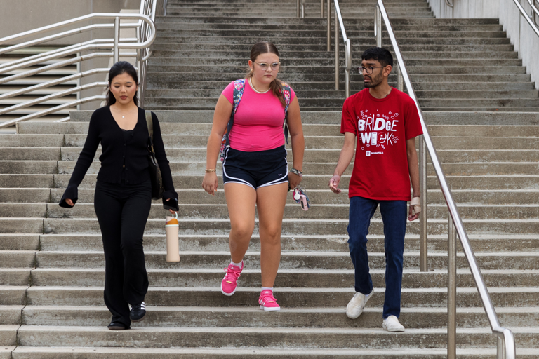 Students walk down stairs while talking.
