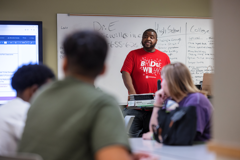 A person wearing a IU Indianapolis Bridge Week shirt is lecturing others.