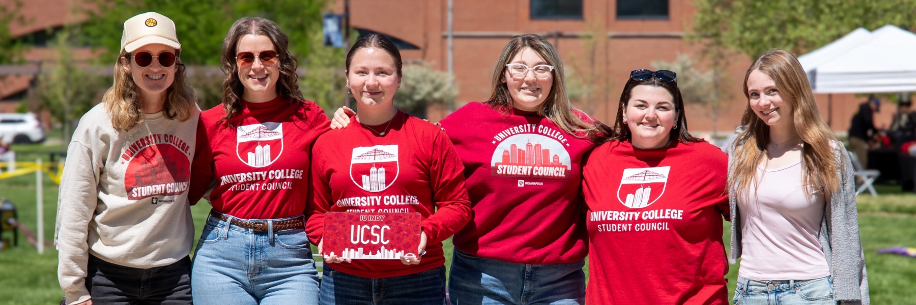 Six people in University College Student Council branded attire pose for a picture outdoors. 